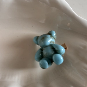 Detailed close-up of a blue marble texture bear hair clip with a gold metal clamp