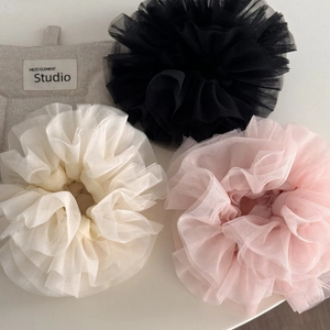 Detailansicht von rosa, cremefarbenen und schwarzen Scrunchies aus mehrlagigem Netzgewebe