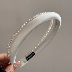 Detail view of the silk satin headband with elegant pearls and handmade fabric label