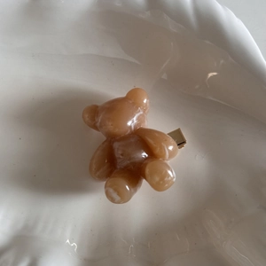 Detailed close-up of a translucent amber bear hair clip with golden metal fastener