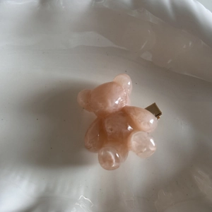 Detail of a pink translucent resin bear hair clip with a gold metal duckbill fastener