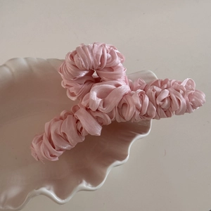 Detailed view of pink silk satin wrapped hair claw clip with pleated texture on a tray