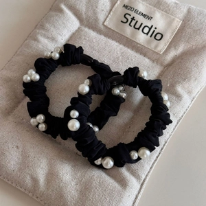 Detail of two black high-elastic hair scrunchies with elegant white faux pearl clusters