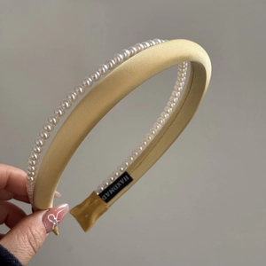 Close-up of handmade double-layer pearl headband with yellow satin finish and inner label