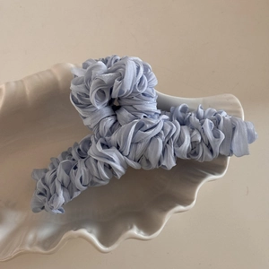 Detailed texture of light blue pleated silk fabric wrapped on a large hair claw clip