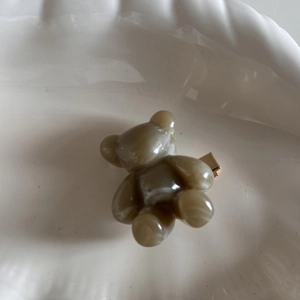 Detailed view of a brown marble-textured resin bear hair clip on a white ceramic plate