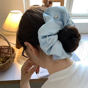 Light blue satin scrunchie with white pearls and silver heart pendant on hair bun