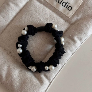 Macro shot of black pleated silk scrunchie adorned with elegant white faux pearls