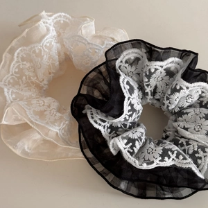 Detailed close-up of vintage cream and black hair scrunchies with intricate floral lace trim