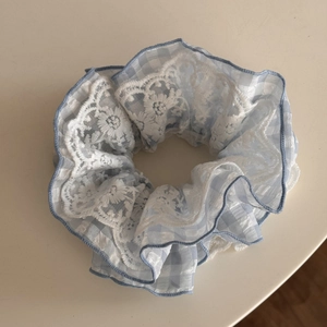 Close-up of blue plaid scrunchie featuring elegant double-layer white floral lace details