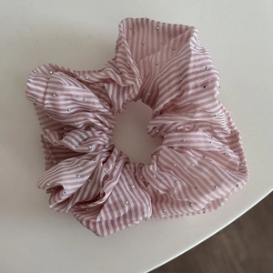 Détail du chouchou en tissu rayé rose et blanc avec des rivets argentés décoratifs