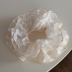 Detailed close-up of vintage beige embroidery lace scrunchie with intricate floral patterns