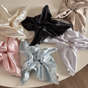 Flat lay of satin scrunchies with long ribbons in white, black, champagne, and blue