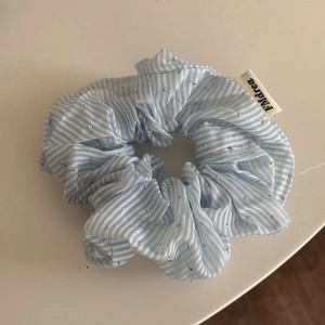 Vue détaillée d'un chouchou en tissu à rayures bleues orné de strass argentés brillants