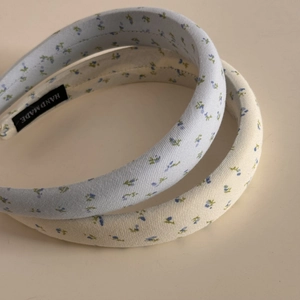 Detailed close-up of blue and beige floral cotton padded headbands with handmade labels
