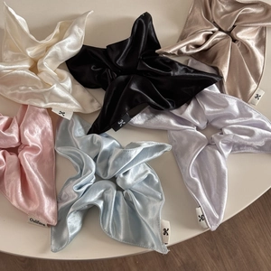 Detailed close-up of six premium glossy satin hair scrunchies in assorted soft colors