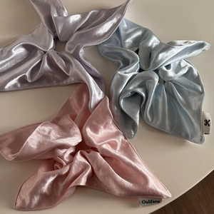 Three premium satin silk scrunchies in pink, blue, and purple displayed on a beige surface
