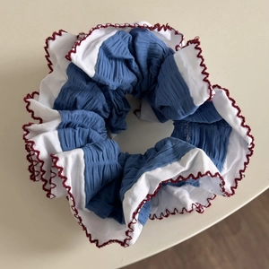 Gros plan détaillé d'un chouchou bleu et blanc avec des coutures ondulées rouges
