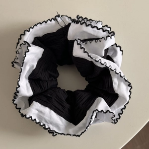 Vue détaillée du chouchou noir avec bords plissés blancs et coutures contrastées chic