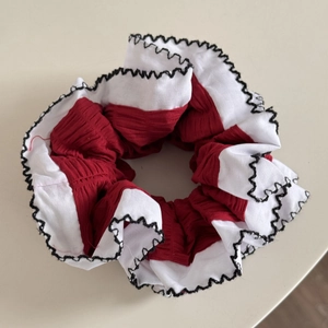 Détail d'un chouchou plissé rouge et blanc avec bords ondulés noirs pour cheveux