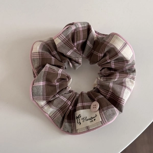 Detail showing checkered fabric texture, pink piping, and handmade label with button
