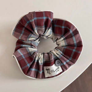 Detailed view of plaid scrunchie with a decorative grey button and handmade cloth label
