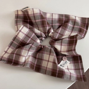 Detail of checkered hair scrunchie featuring a pink button and handmade textile label