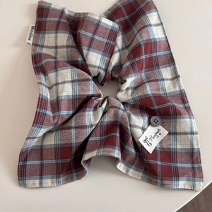 Close-up of plaid fabric scrunchie with a decorative button and handmade label detail