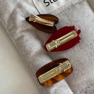 Detail of three cute resin hair clips with golden metal duckbill clips on a soft background