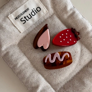 Detail of strawberry and heart hair clips on linen pouch with tortoiseshell texture