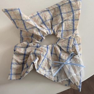 Détail du chouchou à carreaux avec bordure en dentelle et petit nœud bleu clair