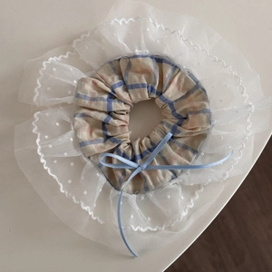 Détail du chouchou à carreaux avec bordure en dentelle et nœud en soie bleu clair