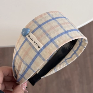 Détail d'un serre-tête à carreaux avec breloque cœur bleu et étiquette faite à la main