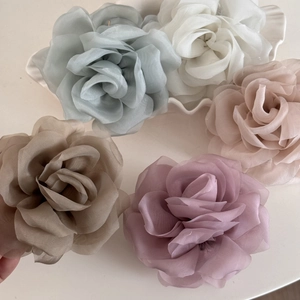 Detail of five chiffon rose hair claws in Morandi colors on a white ceramic tray