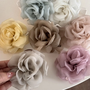 Detail showing various colors of layered chiffon rose hair claws on a white surface