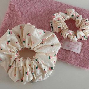 Detailed view of white fabric scrunchies with strawberry prints and brand woven label