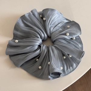 Detail view of grey-blue pleated chiffon scrunchie with white pearl embellishments