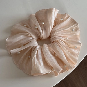 Detail of champagne pearl pleated chiffon scrunchie with beaded texture and soft glow