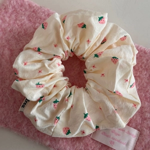 Close-up of cream-white fabric scrunchie with cute strawberry and star prints