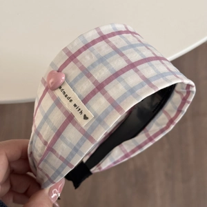 Détail du serre-tête à carreaux rose et bleu avec breloque cœur et étiquette