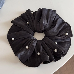 Detail of black pleated pearlescent chiffon scrunchie featuring elegant white faux pearls