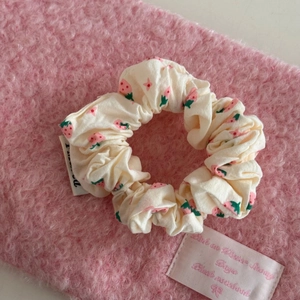 Close-up of a cream scrunchie with pink strawberry patterns on a soft pink background
