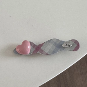 Détail d'une pince à cheveux à carreaux avec cœur rose brillant et breloque Love argentée