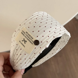 Dettaglio di un elastico per capelli bianco a pois rossi con bottone vintage
