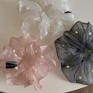 Detailed macro of three organza pearl scrunchies in white, pink, and grey colors