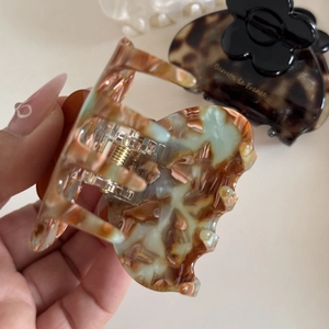 Detail shot of tricolor marble pattern resin hair claw with golden metal spring
