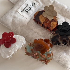 Detailed macro view of acetate flower claw clips set on a rustic linen bag background