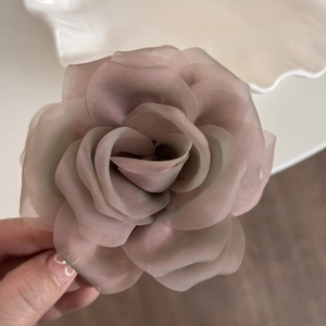 Detail of dusty rose organza rose hair claw showing delicate layers of translucent petals