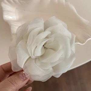 Detailed macro view of white organza rose flower hair claw with translucent layered fabric petals