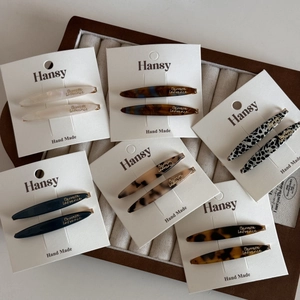Close-up of assorted acetate leaf barrettes with gold lettering on a velvet jewelry tray